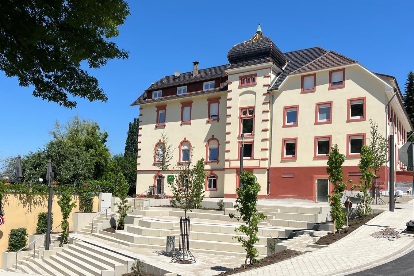 Außenansicht eines hellen Beherbergungshauses mit Freitreppe